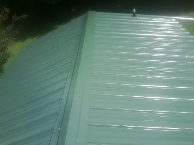 New green metal panels meeting at the ridge of a roof — Flat Roof Repair work by our crew in East Millsboro