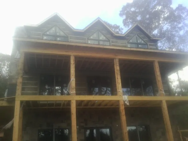 Dormers and porch framing on a large log home under construction — Roof Coating work by our crew in East Millsboro