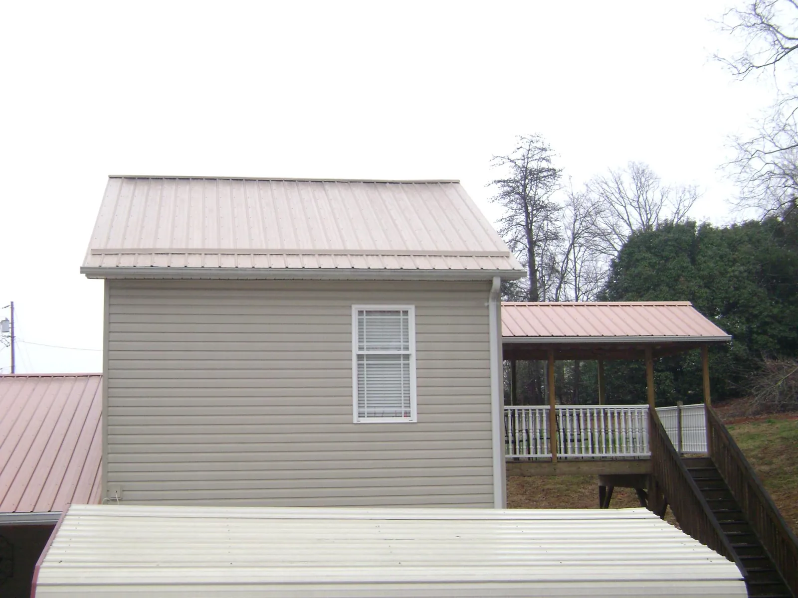 Tan metal roofs on a two story addition and attached porch, from a Roof Replacement job in East Millsboro