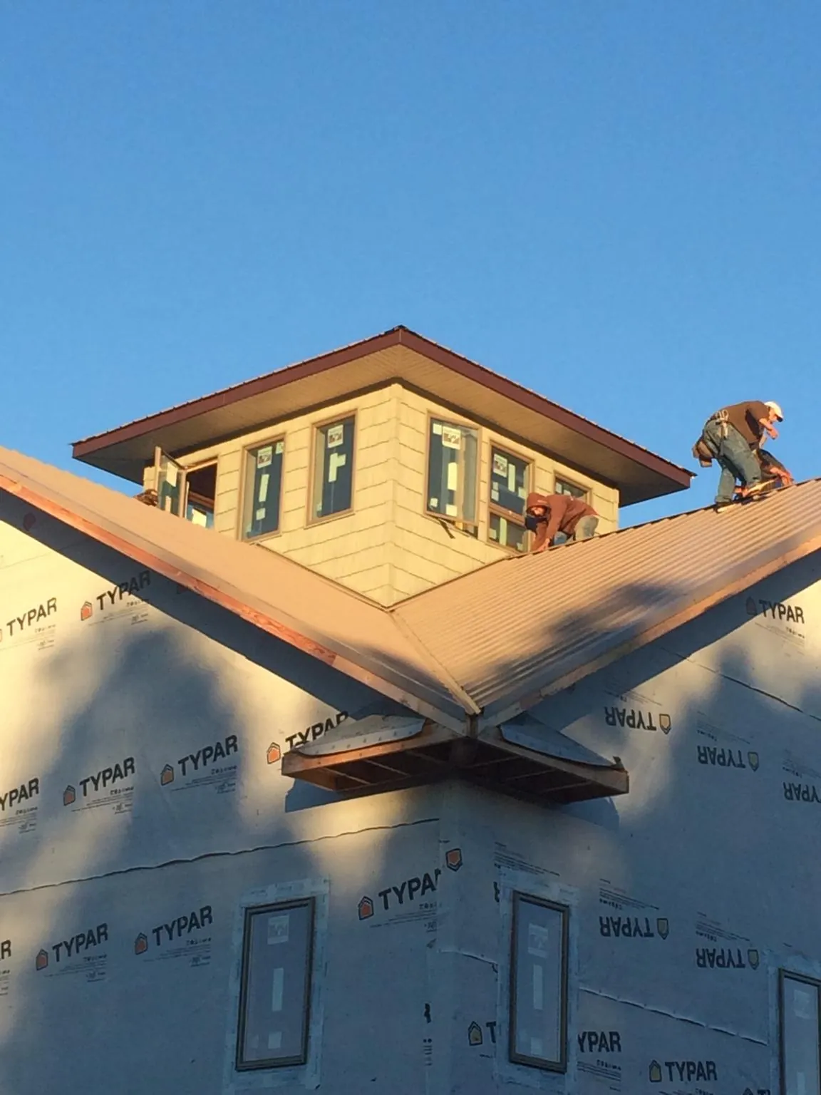 Roofers working around a rooftop cupola on a new metal roof at sunset — Roof Waterproofing in East Millsboro by Roofing Brothers